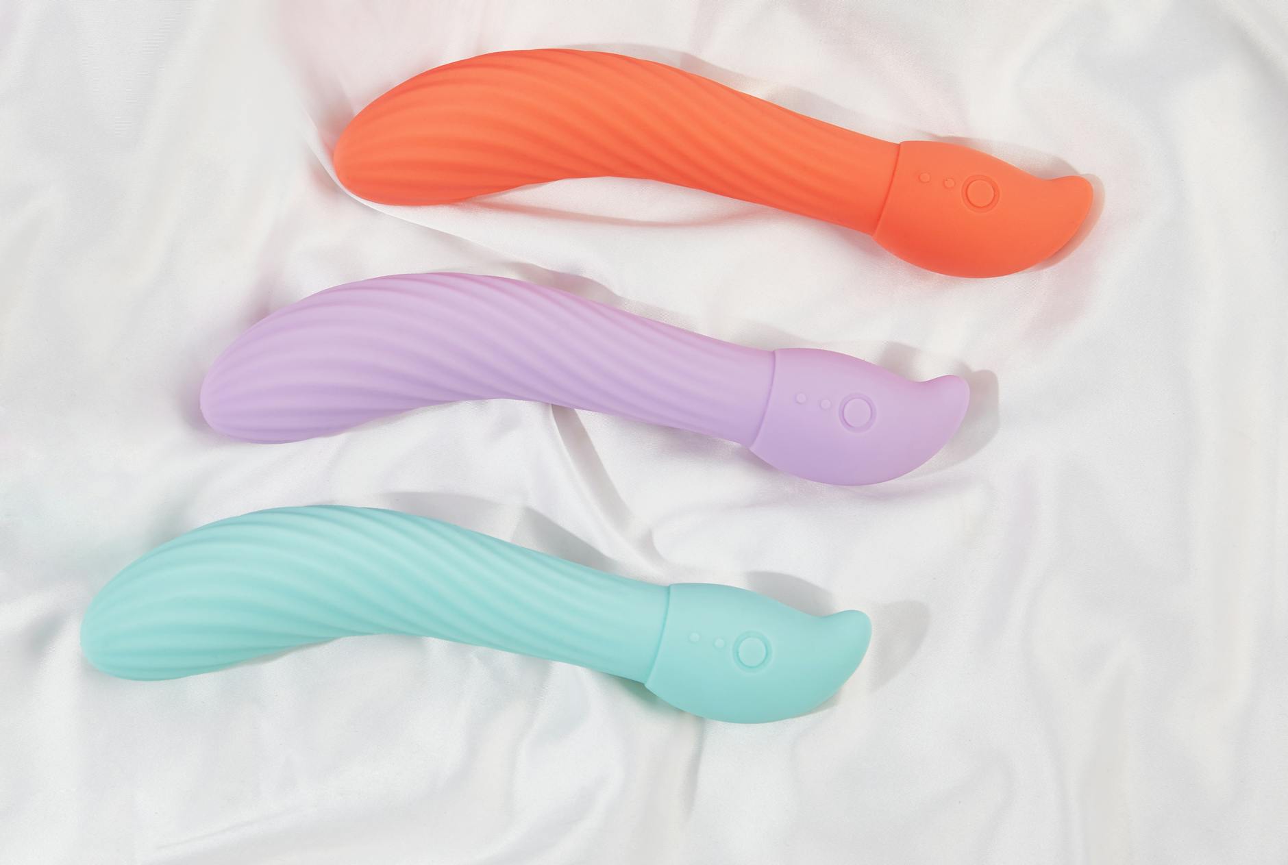 Hand holding a vibrant orange vibrator against a purple minimalist background