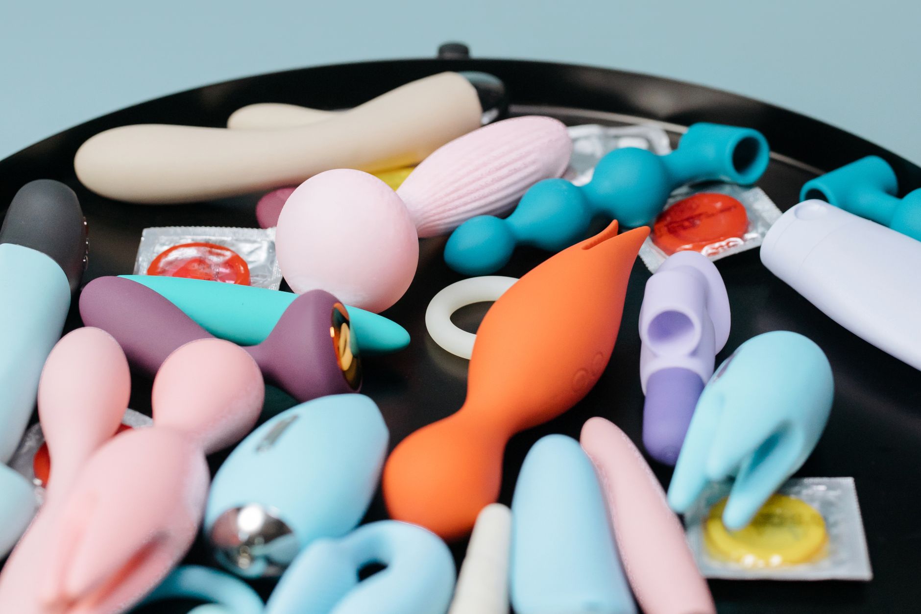 A curated collection of various clitoral vibrators and sexual wellness toys displayed on a black surface.
