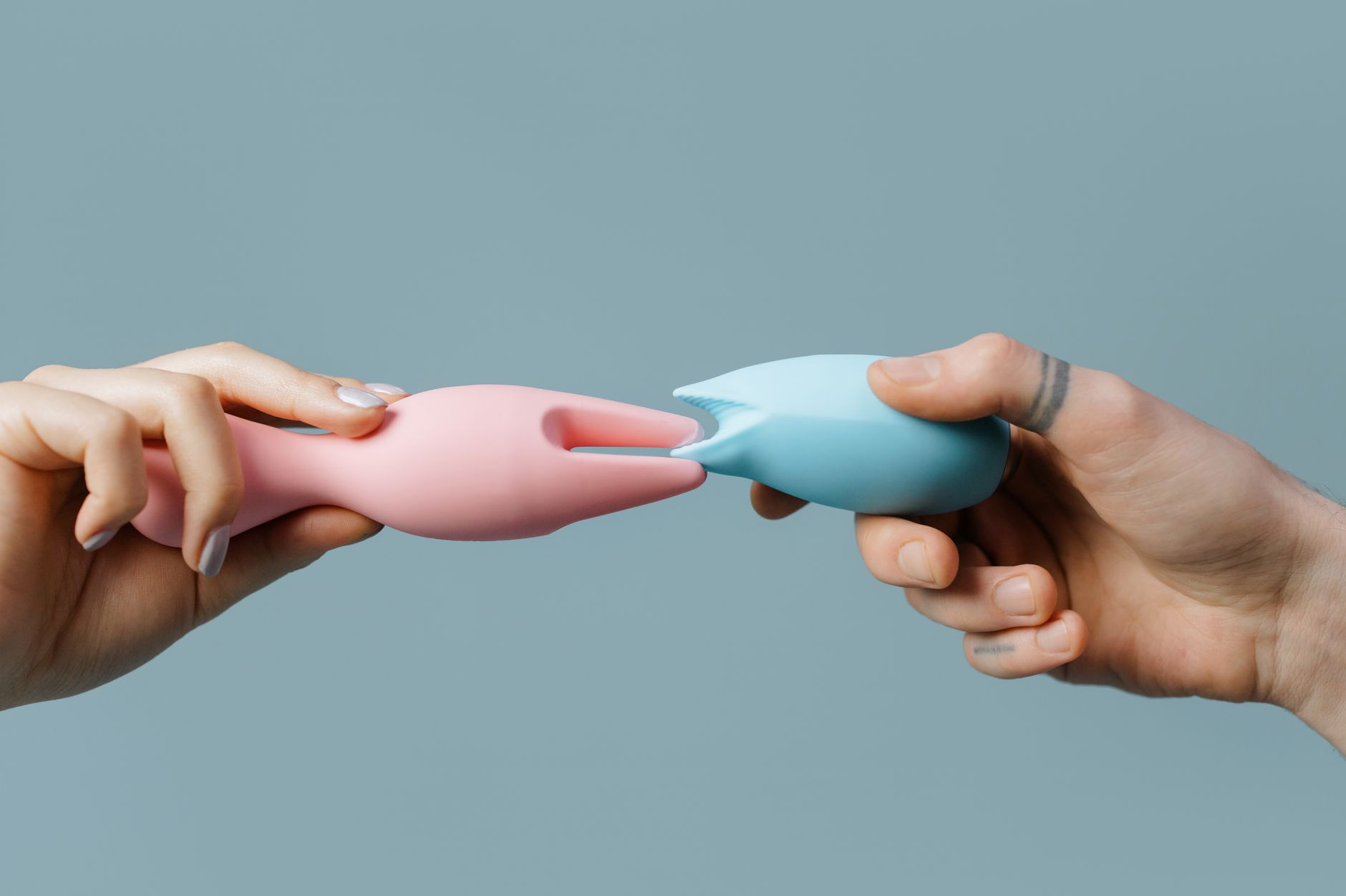 Hands holding colorful silicone vibrators, representing diverse pleasure tools for different bodies
