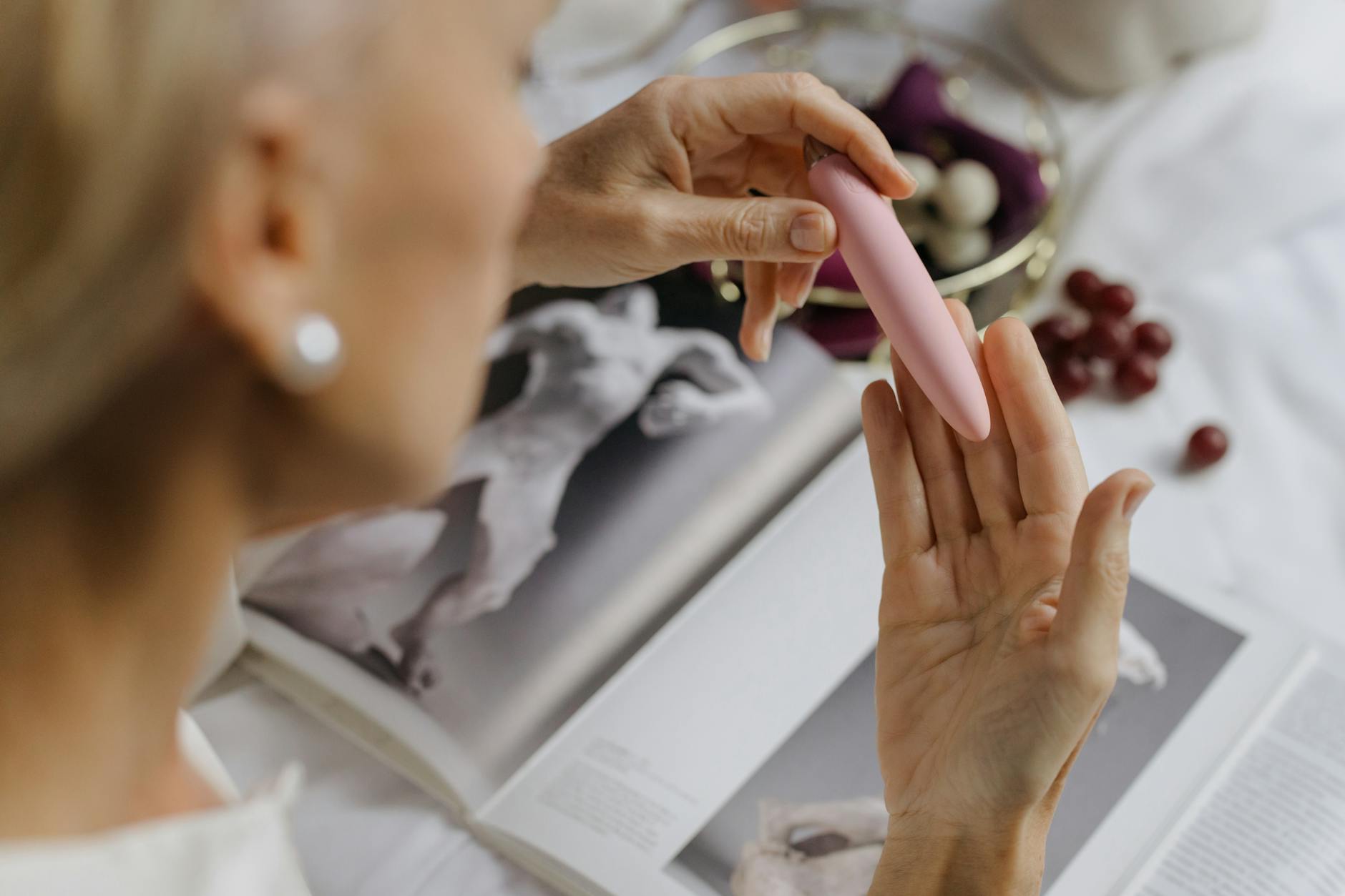 Close-up of hands holding a sleek clitoral vibrator, symbolizing intimate exploration with a partner
